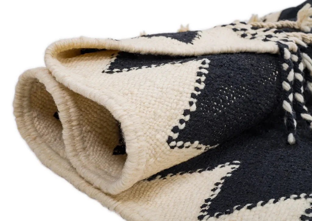 A folded black and white woven piece featuring a geometric zigzag pattern adds a touch of elegance to any room.