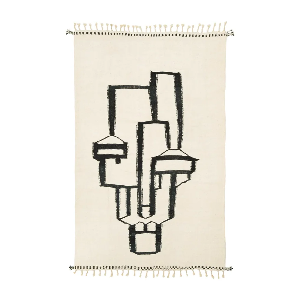 Discover a beige rug featuring an intricate black abstract geometric design that hints at a human figure. The piece is beautifully finished with fringed edges, adding a touch of sophistication to any room.