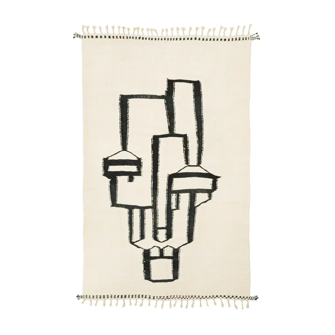 Discover a beige rug featuring an intricate black abstract geometric design that hints at a human figure. The piece is beautifully finished with fringed edges, adding a touch of sophistication to any room.
