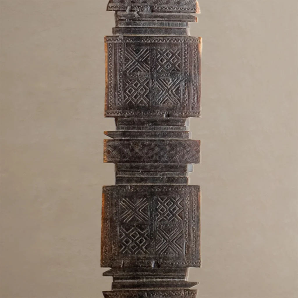 Close-up of a hand-carved wooden column featuring intricate geometric patterns, reminiscent of vintage craftsmanship akin to an ornate tent peg.