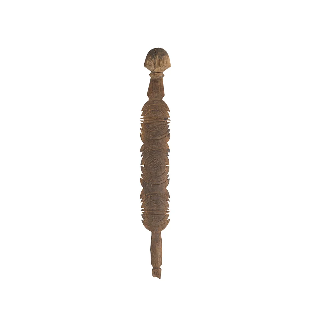 A hand-carved vintage wooden object with ornate patterns, a rounded top, and a tapered end, featuring symmetrical, intricate designs along its length—perfect as an elegant tent peg or decorative piece.