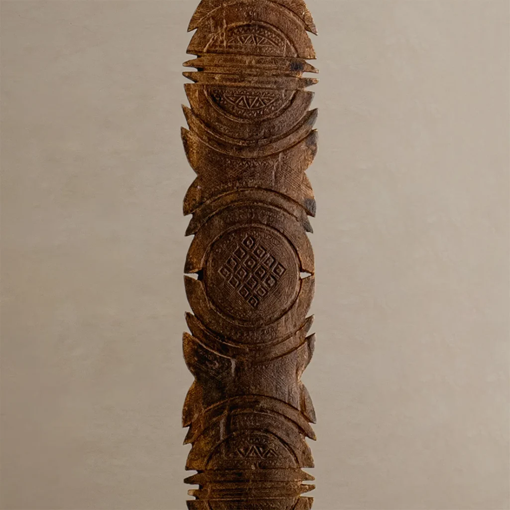Intricately hand-carved vintage wooden sculpture with geometric patterns, featuring circular and linear designs reminiscent of a tent peg.