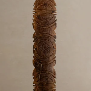 Intricately hand-carved vintage wooden sculpture with geometric patterns, featuring circular and linear designs reminiscent of a tent peg.