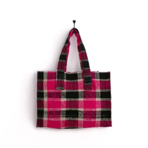 Plaid tote bag with pink, black, and white checkered pattern, hanging on a wall hook.