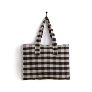 A black and white checkered tote bag is hanging on a wall hook.