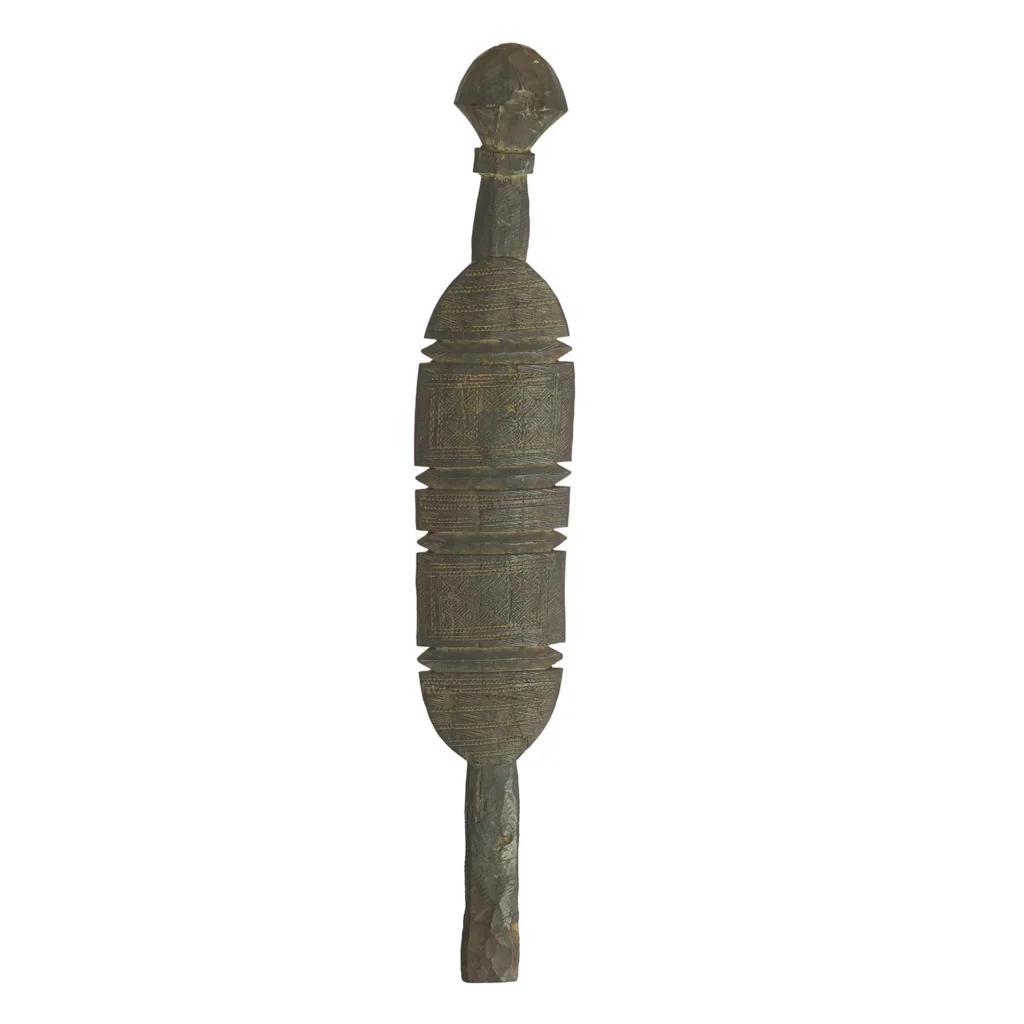 A hand-carved vintage wooden artifact features an elongated, tent peg-like design with a central circular section and symmetrical patterns, topped with a rounded shape against a plain white background.