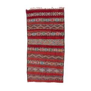 A traditional woven rug adorned with red, green, and white geometric patterns and fringed edges adds a touch of cultural elegance to any space.