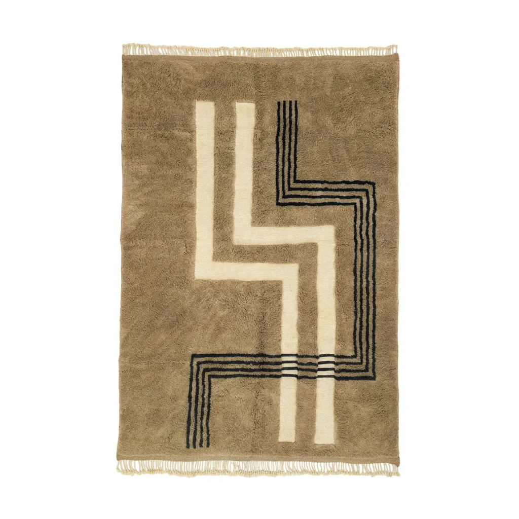 A luxurious Moroccan rug, hand-knotted in a striking geometric pattern of black and cream lines intersecting at right angles, crafted in elegant beige and brown tones. The rug features fringes on the shorter edges for added texture and style.