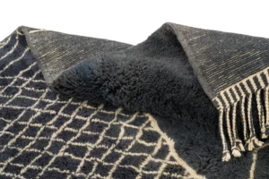 A luxurious black and white patterned rug, hand-knotted with a unique design and tasseled edge, exudes the elegance of a Moroccan rug.