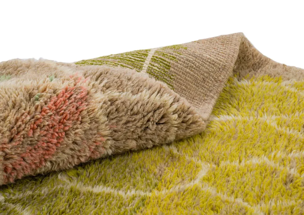 A close-up view of a multi-colored textured fabric with a geometric pattern, featuring one corner folded to reveal its soft underside.