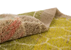 A close-up view of a multi-colored textured fabric with a geometric pattern, featuring one corner folded to reveal its soft underside.