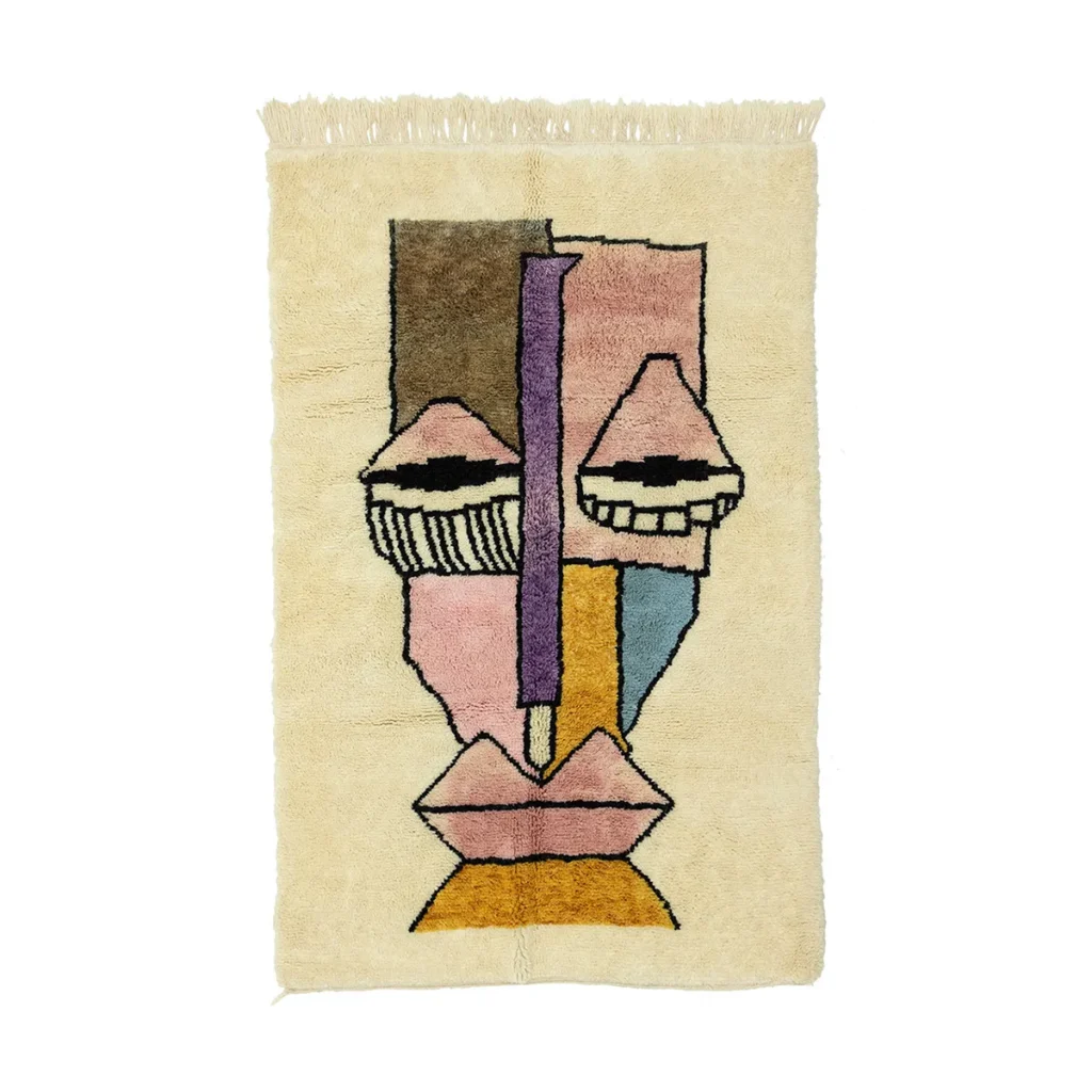 This hand-knotted beige rug boasts an abstract face design in pink, brown, blue, and yellow hues. Geometric shapes and bold outlines highlight the artistic flair. Perfect for adding a touch of originality to any room.
