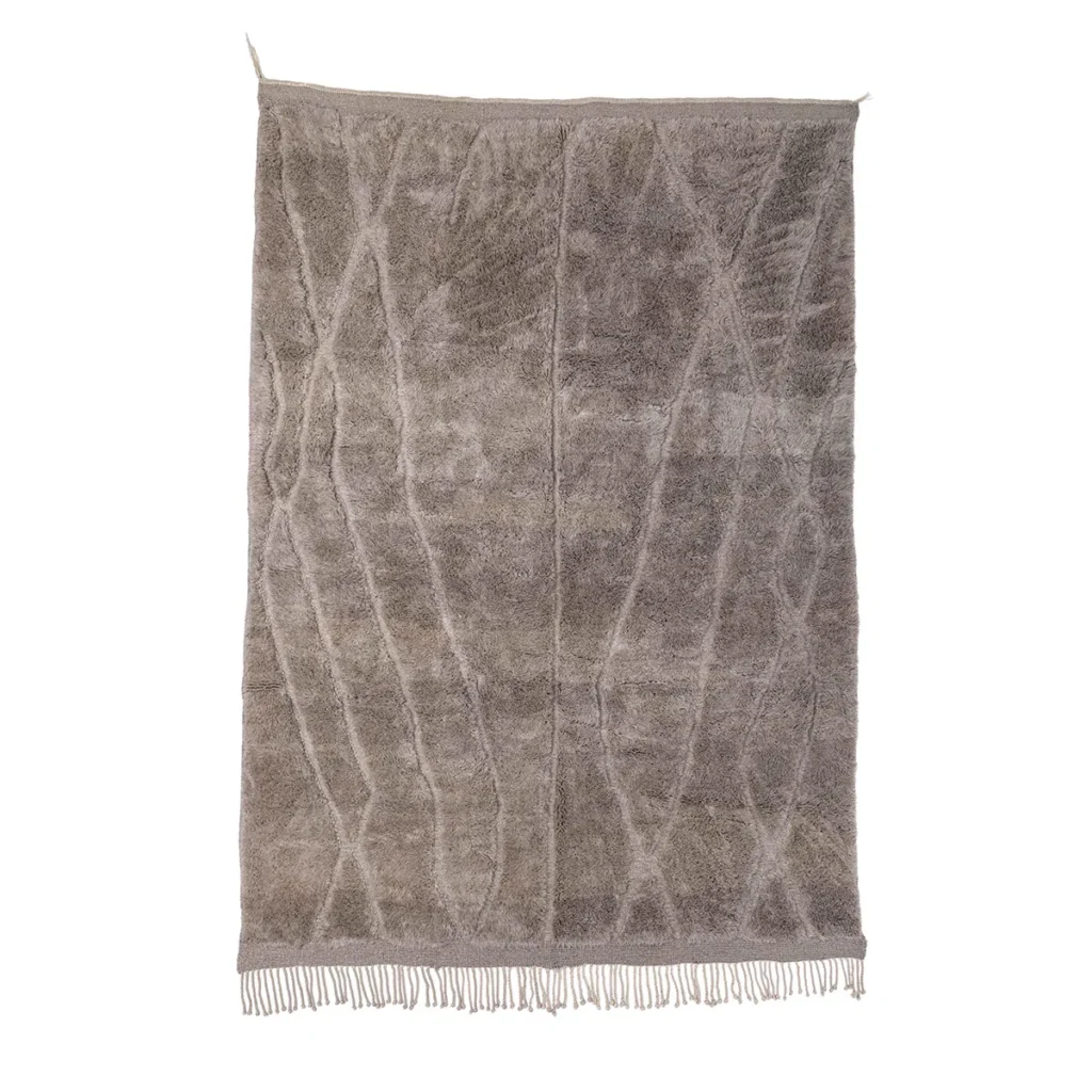 A rectangular, beige hand-knotted rug with a textured, intersecting line pattern and fringe along the bottom edge, set against a white background.