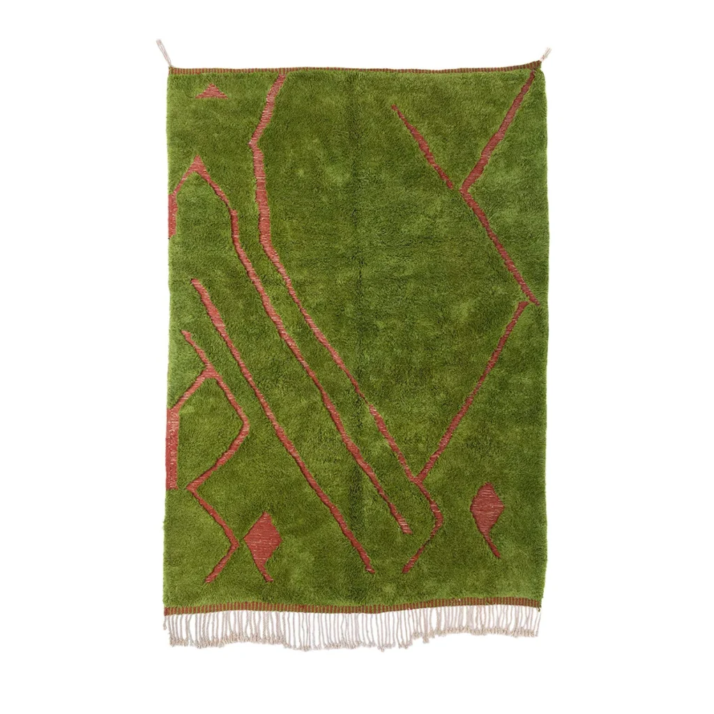 A vibrant green rectangular rug with striking red geometric patterns and fringe at the bottom elegantly hangs on a wall, adding bold visual interest to any space.