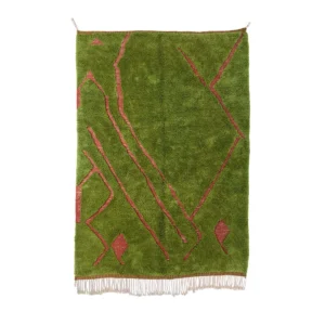 A vibrant green rectangular rug with striking red geometric patterns and fringe at the bottom elegantly hangs on a wall, adding bold visual interest to any space.