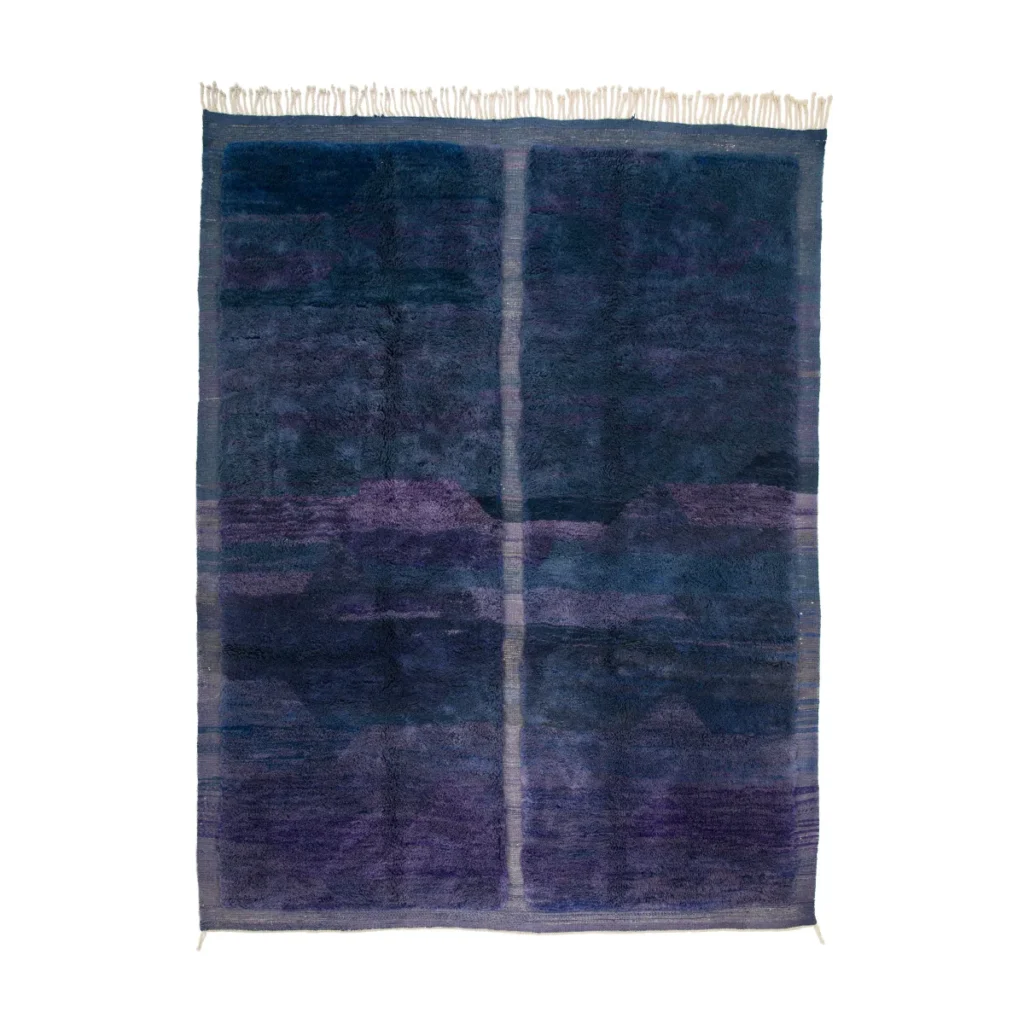 A rectangular rug with a deep blue and purple gradient pattern, featuring faint vertical lines and fringes on its shorter edges. Perfect for those seeking luxury, this hand-knotted masterpiece adds elegance to any room.