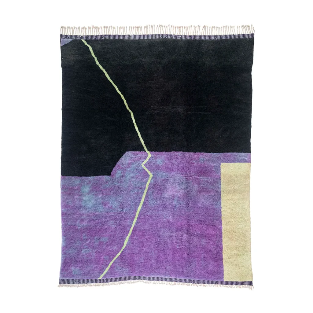 This luxurious hand-knotted Moroccan rug showcases an abstract geometric design with a dark upper section accentuated by a jagged green line. The lower area features a textured blend of purple and light beige, complemented by fringes at both the top and bottom.