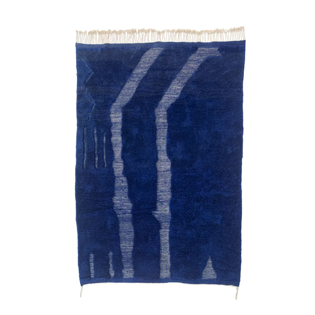 This luxurious blue rectangular rug features abstract light blue patterns and fringed edges at the top, embodying the elegance of a Moroccan hand-knotted design.