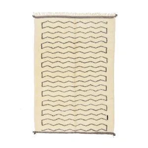 This luxury rug is rectangular and beige, featuring hand-knotted black zigzag patterns running horizontally. The fringed edges add a touch of elegance.