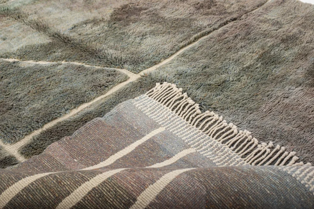 In this cozy close-up, two layered rugs create a stunning visual contrast. The top one boasts a thick, fuzzy texture, while the bottom rug showcases a vibrant striped pattern with fringed edges.