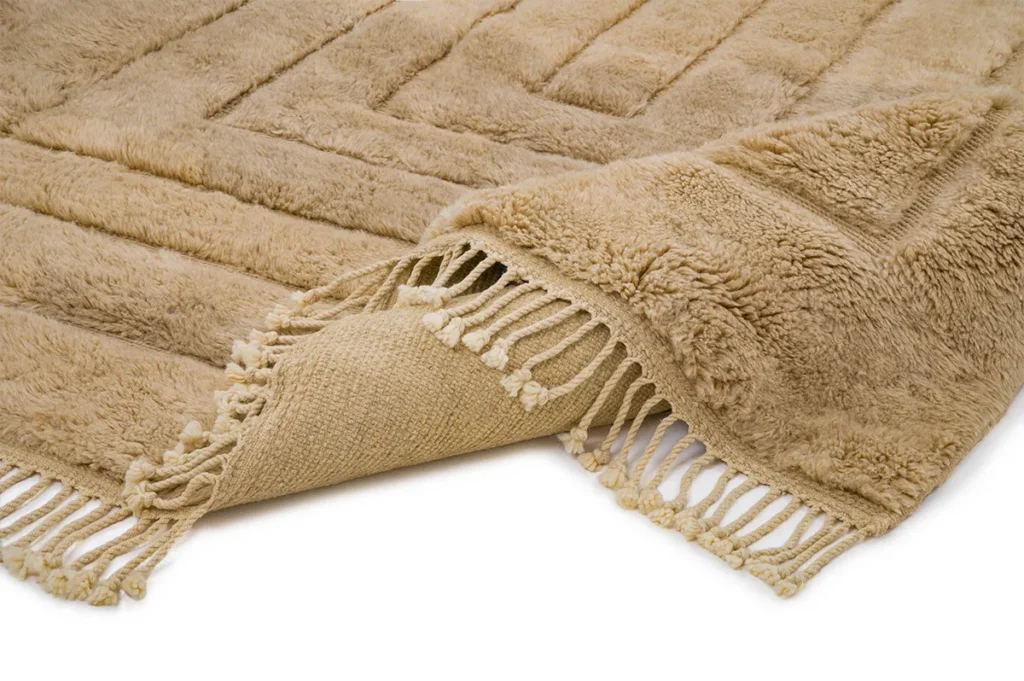 A beige, textured Moroccan rug is partially folded over, revealing its intricately woven underside.