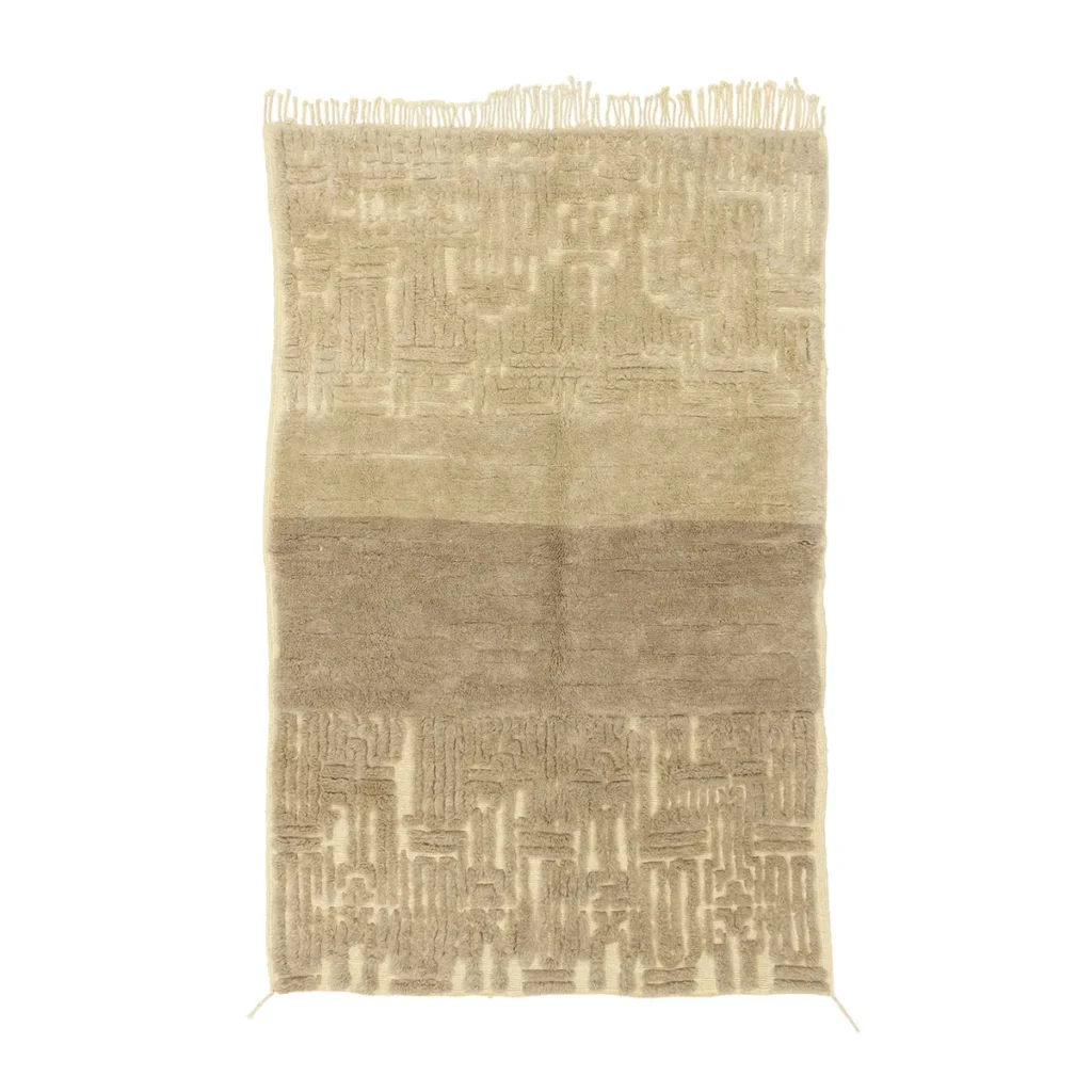 A luxurious beige rectangular rug, hand-knotted with a textured geometric pattern and elegant fringe on one end.