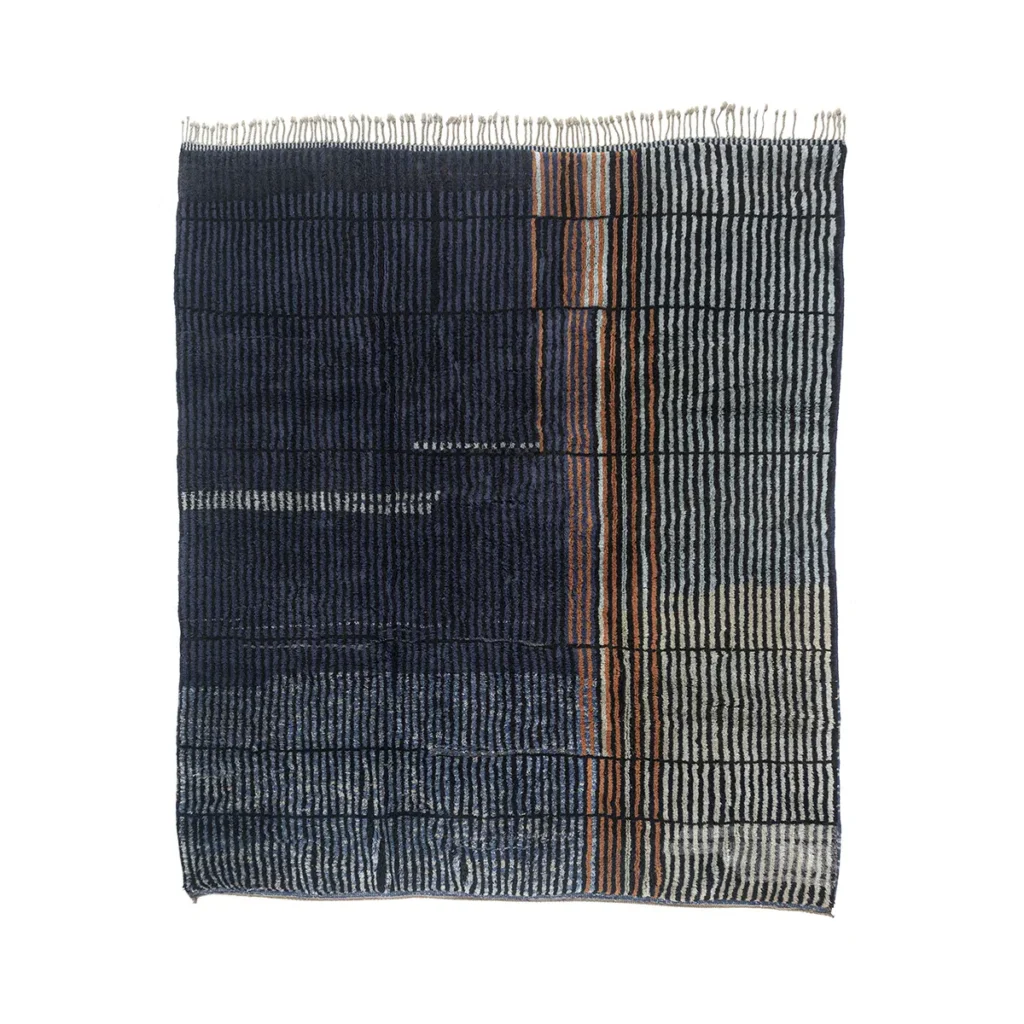 A hand-knotted Moroccan rug featuring a grid pattern of vertical and horizontal stripes in navy, orange, and white with uneven fringes on top, offering a touch of luxury to any space.