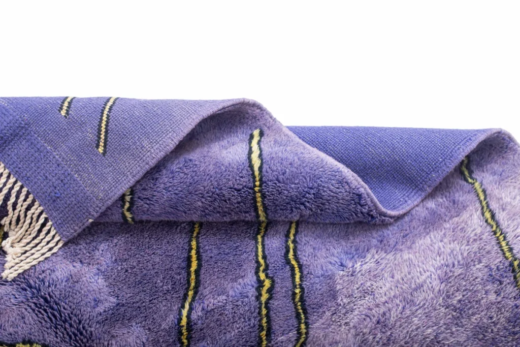 A luxurious, purple woolen piece with black and yellow stripes sits against a white background, crafted with the elegance found in hand-knotted rugs.
