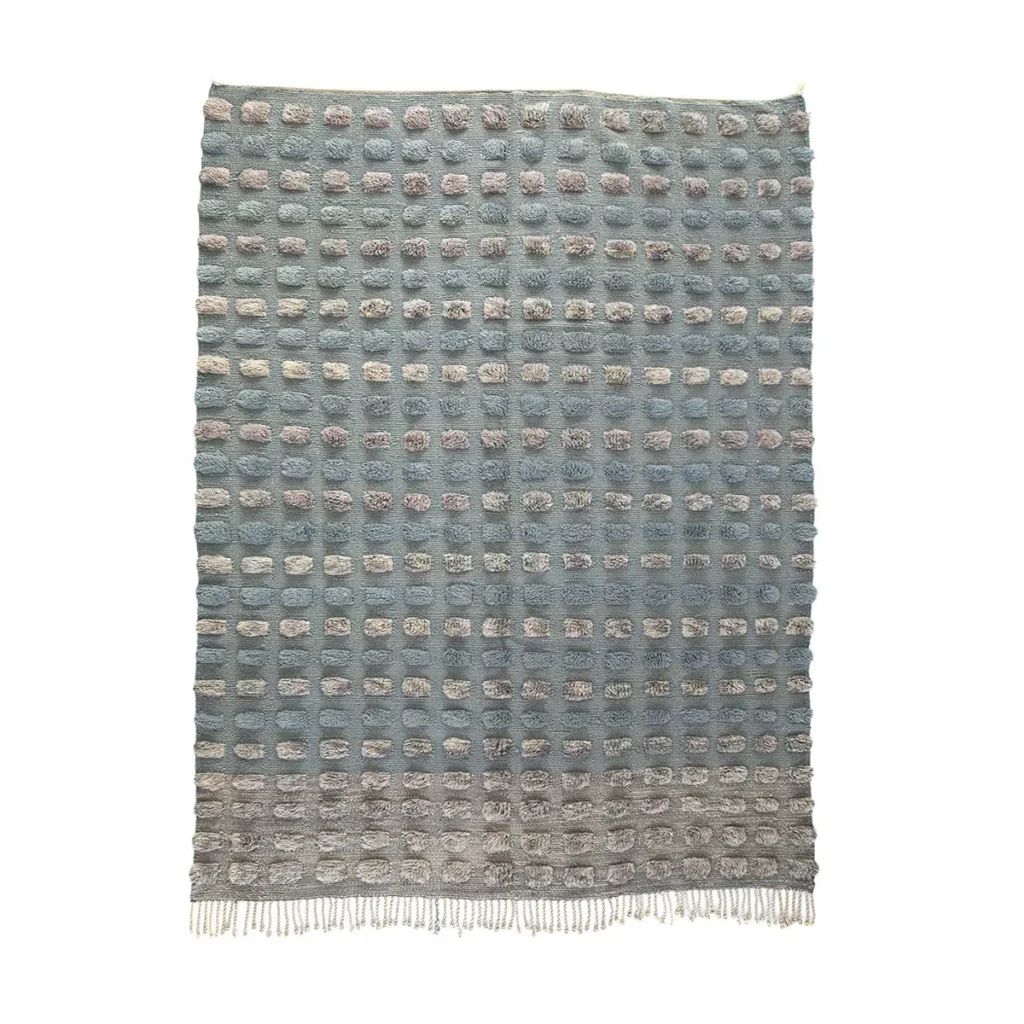 A blue and gray luxury rug featuring a grid of raised oval shapes and fringed edges, hand-knotted for exquisite detail.