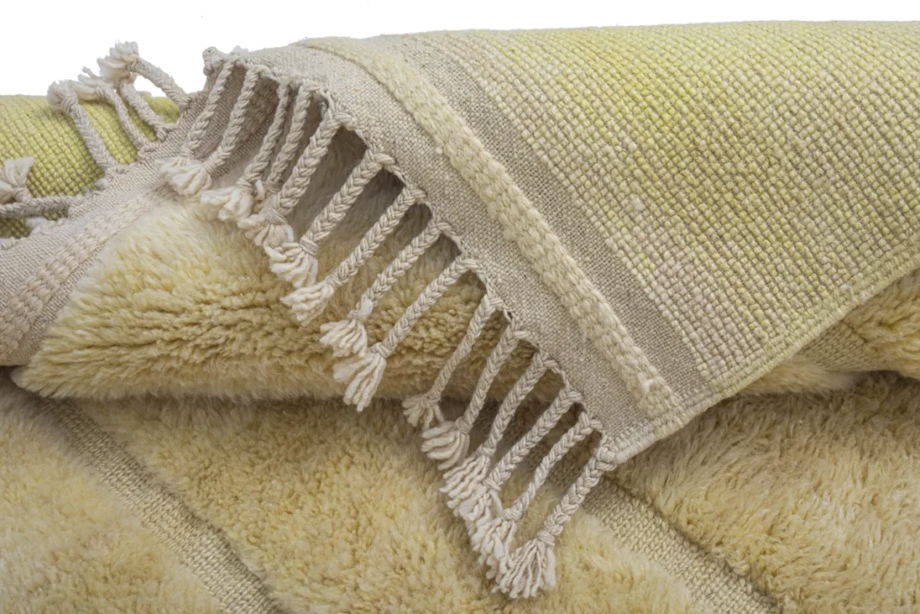 Close-up of a folded, fringed yellow textile with a textured brown stripe, featuring both fuzzy and woven sections for added charm.