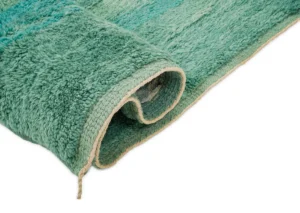 This close-up showcases a luxurious rolled green textured rug with a beige trim, set against a white background.