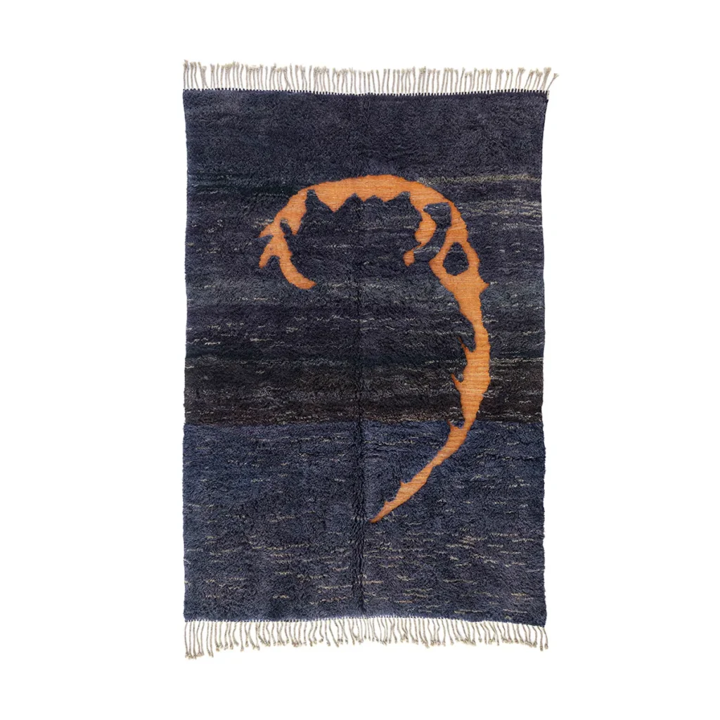This captivating blue and black rug features an abstract orange design at its core, highlighted by an elegant fringe along the edges.