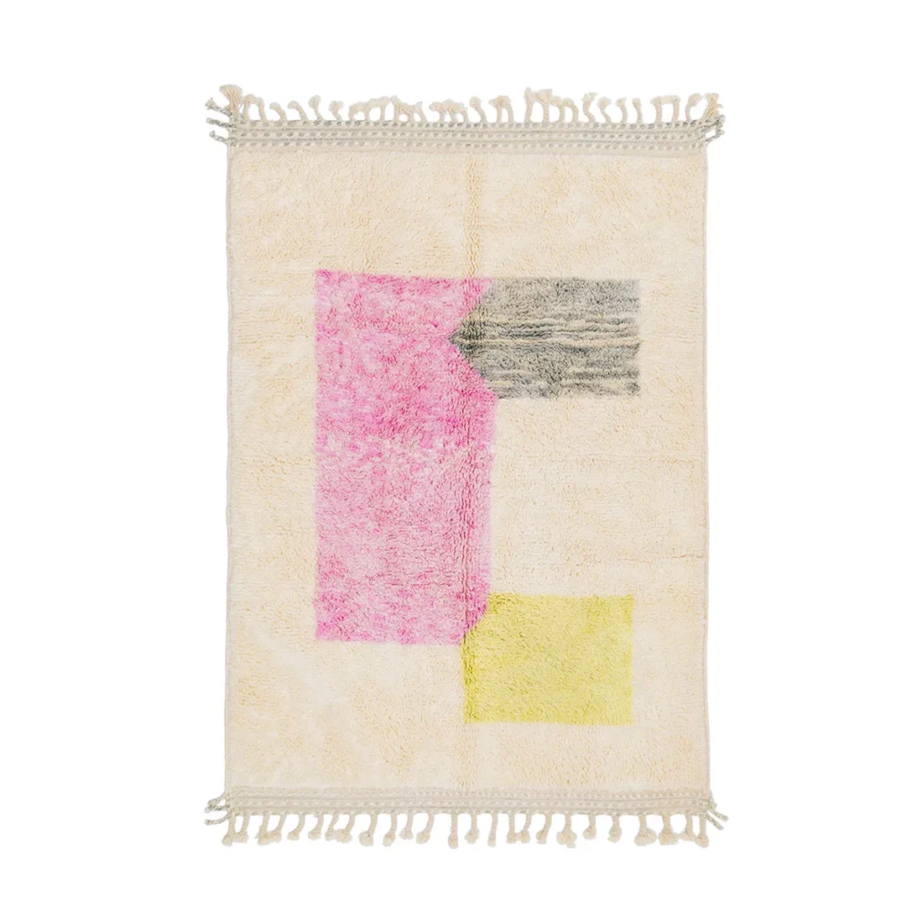 A rectangular rug with fringed edges, showcasing a cream backdrop adorned with abstract geometric shapes in pink, gray, and yellow. This elegant piece effortlessly adds a touch of sophistication to any living space.
