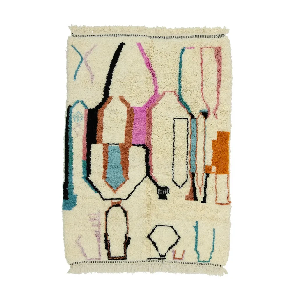 This hand-knotted, rectangular wool rug boasts an abstract design with a cream background adorned by geometric shapes in pink, blue, orange, and black. The authentic Moroccan rug features fringed edges for added texture.