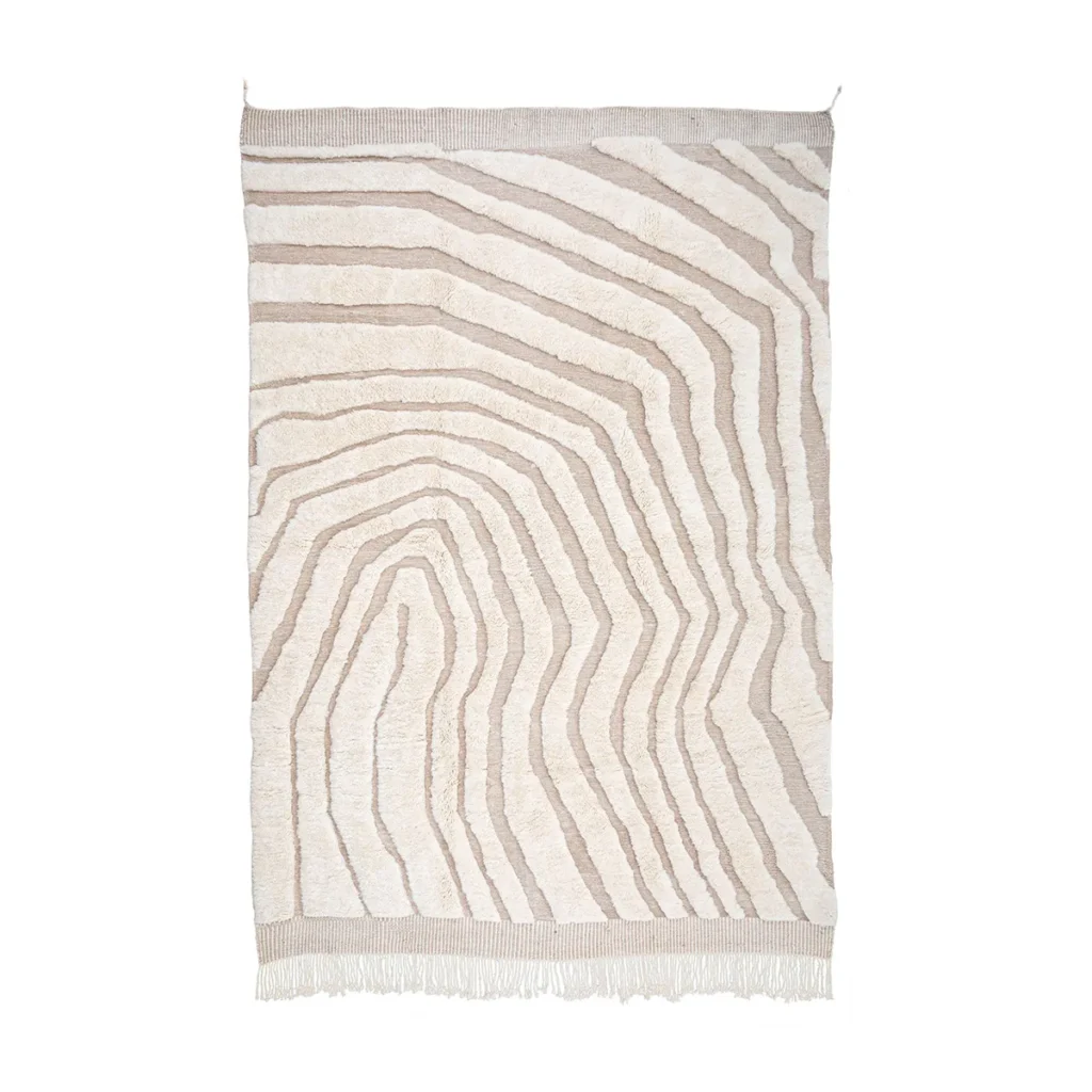 This luxurious, beige and white rug boasts an abstract wavy line pattern and hand-knotted craftsmanship, complete with fringed edges at the bottom.