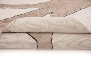 A close-up of a partially rolled beige and brown luxury rug with a geometric pattern, highlighting its intricate texture and design details.