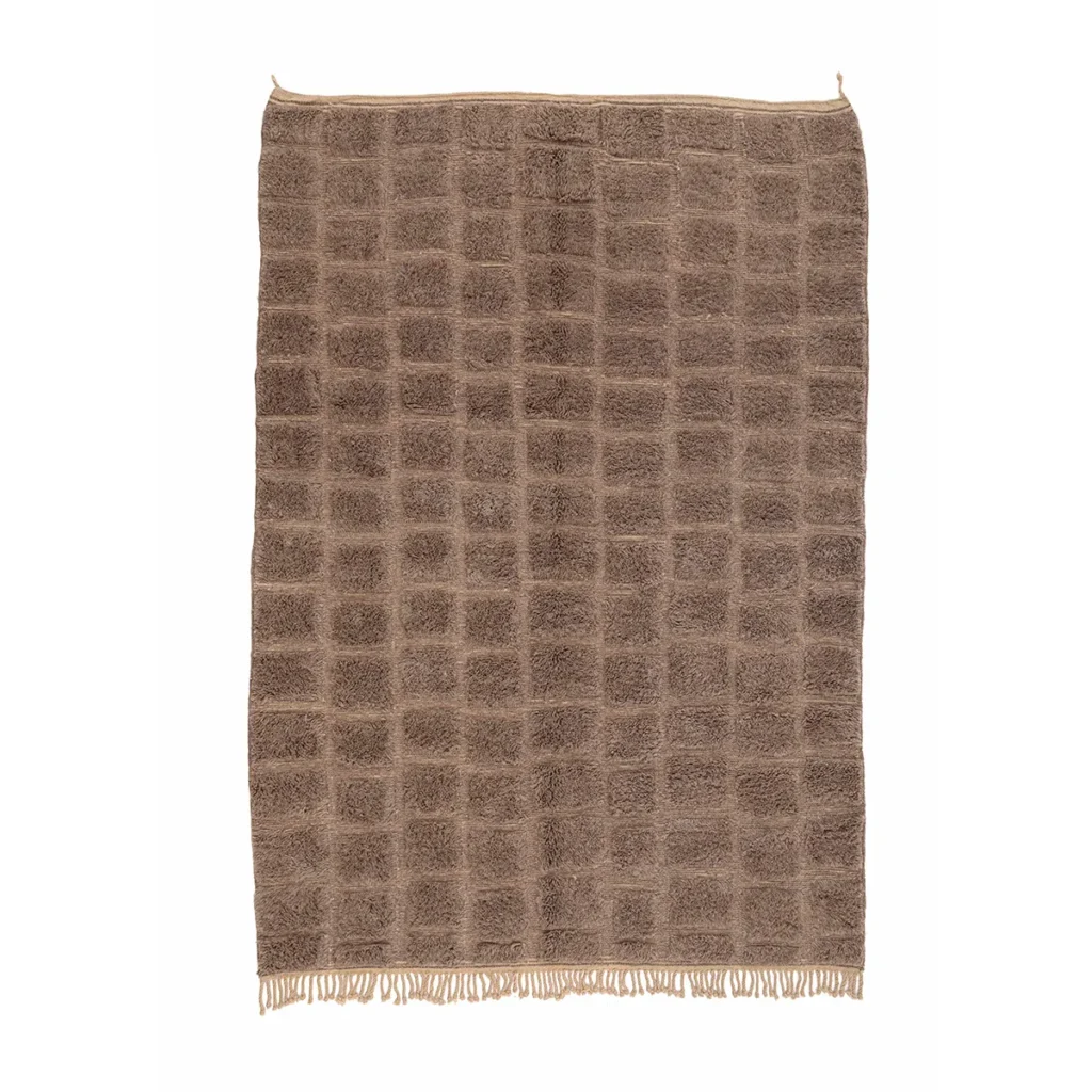 A luxurious beige piece with a grid-like texture and fringed edges is displayed against a white background, reminiscent of high-end hand-knotted rugs.