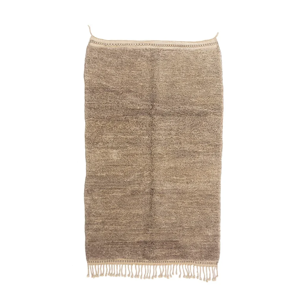 This hand-knotted Moroccan rug is rectangular in shape and showcases a beige woven design with fringed edges and a simple stitched border, set against a white background.