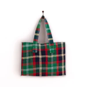 Checkered tote bag in red, green, blue, and beige hangs on a wall hook.
