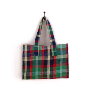 A multicolored plaid fabric tote bag hangs on a wall hook.