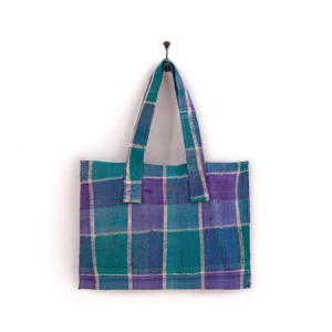 A blue and purple plaid tote bag with two straps hanging on a single nail against a plain white background.