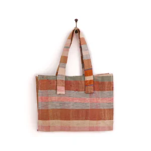 A woven tote bag with a checkered pattern in shades of pink, brown, and beige hangs from a wall hook.