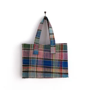 A rectangular tote bag with a multicolored plaid pattern hangs against a white background.