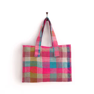 A multicolored plaid tote bag with shades of pink, blue, green, and beige hangs on a single hook against a plain white background.