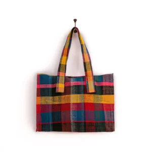 A brightly colored, plaid-patterned fabric tote bag hangs on a wall hook.
