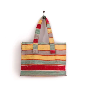 A colorful striped woven tote bag hangs on a wall hook.