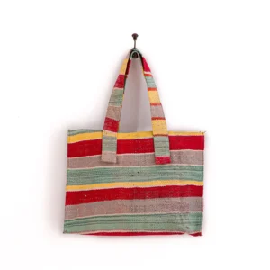 Multicolored striped tote bag with two handles, hanging on a hook against a white background.