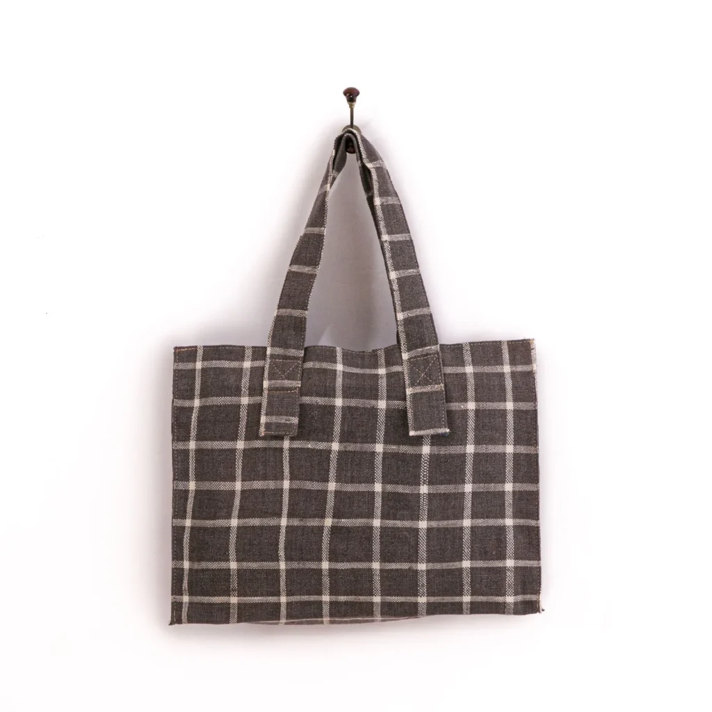 Gray checkered tote bag with two handles hanging on a wall hook.