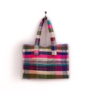 A multicolored plaid tote bag with short handles hangs on a hook against a white background.