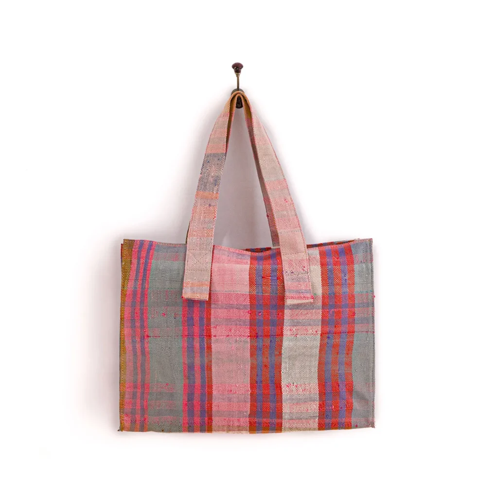 A multi-colored, checkered-patterned tote bag with two handles hangs on a wall hook.
